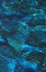 A dynamic abstract painting with rich blue tones and textured brushstrokes evokes movement and depth.